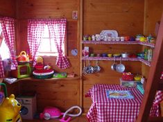 a child's room with wooden walls and red checkered table cloth on the floor