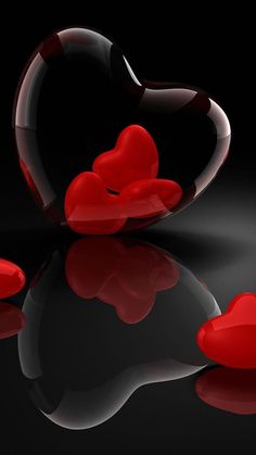 a red heart shaped object sitting on top of a black surface next to some water