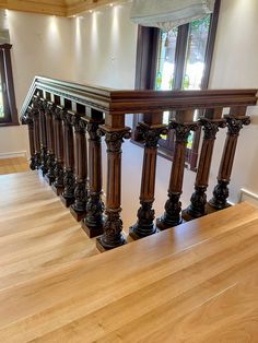 an empty room with wooden railings and windows in the back ground, along with hardwood flooring