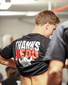 a man with his back turned to the camera, wearing a t - shirt that says thanks hero