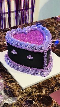 a purple heart shaped cake sitting on top of a table