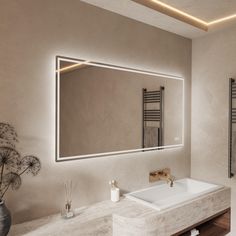 a bathroom with a large mirror above the sink and lights on the wall next to it