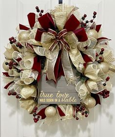 a red and white christmas wreath hanging on a door with the words true love was born in a stable