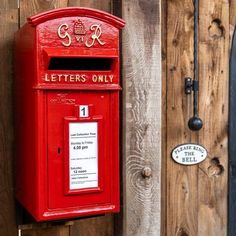 a red mailbox mounted to the side of a wooden fence