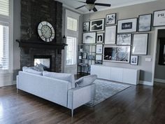 a living room filled with furniture and lots of framed pictures on the wall next to a fireplace