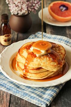 a stack of pancakes on a plate with syrup being drizzled over them