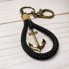 an anchor keychain is shown on a white table with a black braided cord