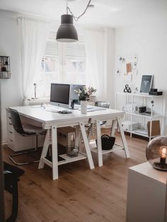 a white desk with two computers on top of it in front of a large window