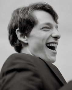 a young man smiling and wearing a suit