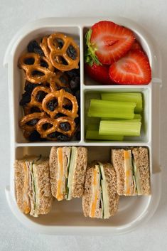 a lunch box filled with sandwiches, fruit and pretzels