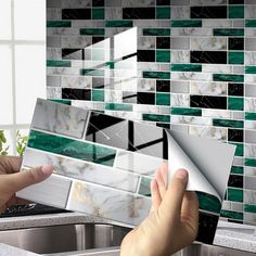 a person is opening the door to a kitchen with green and white tiles on the backsplash