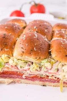 a sandwich cut in half sitting on top of a white plate next to some tomatoes