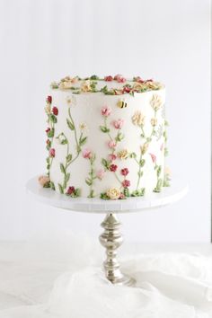 a white cake with flowers on it sitting on top of a table