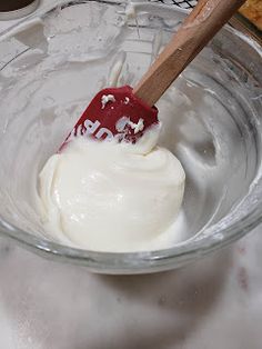 a red spatula in a glass bowl filled with cream