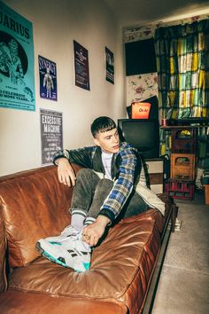 a young man sitting on top of a brown leather couch