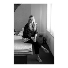 a black and white photo of a woman sitting on a bed