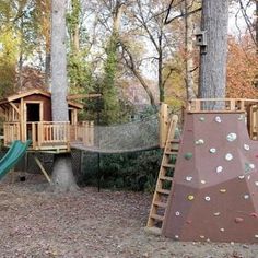 there is a play area in the woods with climbing walls and swings for children to climb on