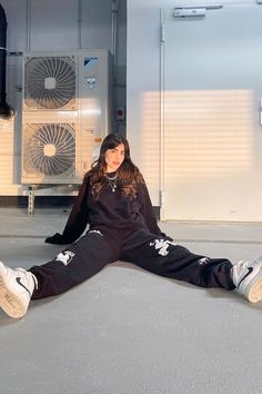 a woman sitting on the ground in front of some air conditioners