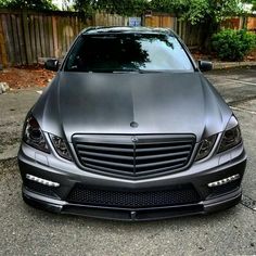 the front end of a mercedes s - class sedan parked in a parking lot next to a fence