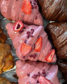 several pastries with strawberries on them are cooling on a rack in front of other pastries