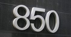 a large metal number sign mounted to the side of a black building with white numbers