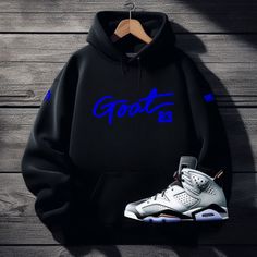 Upgrade your hoodie game with the GOAT 23 Black Sneaker Hoodie. This sleek and stylish hoodie is a perfect choice for anyone looking to make a statement. The bold "GOAT 23" sneakerhead graphic on the front gives a nod to sneaker culture, while the soft and comfortable fabric ensures you'll want to wear it all the time. The adjustable drawstring hood, ribbed cuffs and hem, and front pocket all add to the practicality and style of this men's sneaker hoodie. So why wait? Order now and step up your style game with our exclusive "GOAT 23" sneaker hoodie to match Air Jordan 13 black and blue colorways. With fast shipping times, hassle-free returns, and unbeatable customer service, there's never been a better time to join Threads On Fire! Check out our SneakerThreads Blog for all things sneaker c Black Hoodie With Drawstring Hood For Fans, Black Fan Apparel Hoodie, Black Long Sleeve Fan Apparel Hoodie, Black Fan Apparel Hoodie For Streetwear, Black Hoodie For Streetwear Fan Apparel, Black Streetwear Hoodie Fan Apparel, Black Streetwear Hoodie For Fans, Black Fan Apparel Sweatshirt For Streetwear, Black Graphic Hoodie