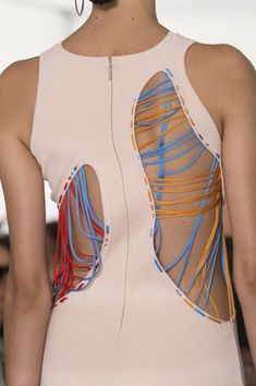 the back of a woman's dress with multiple colored strings on it and an open cutout