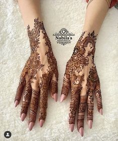 two hands with henna tattoos on them, one is showing off the intricate design