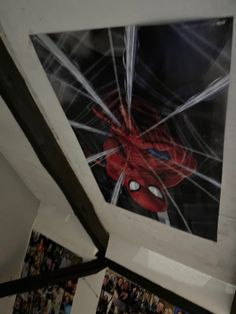 a spiderman poster hanging from the ceiling in a room with pictures on the walls