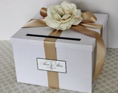 a white box with a brown ribbon and a flower