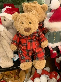 two teddy bears in pajamas and santa hats sitting next to each other on a table