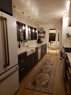 a large kitchen with wooden floors and white walls, along with an area rug on the floor