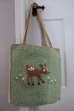 a handbag hanging on a door handle with a deer embroidered on the front and side