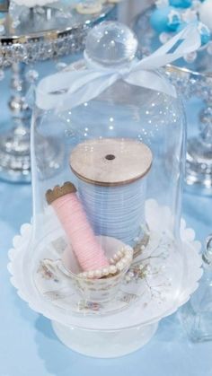 two spools of thread are under a glass clochet on a table