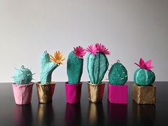 there are many small cactuses in the pots on the table, one is pink and one is green