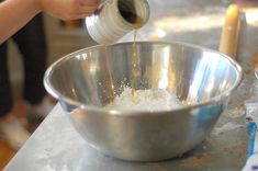 a person pouring batter into a metal bowl