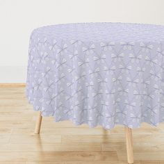 a table covered with a purple and white flowered design on top of a hard wood floor