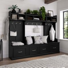 a black and white room with a bench, coat rack, rug and plants on the floor