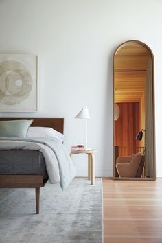 a bedroom with a bed, chair and lamp in it's corner next to a doorway