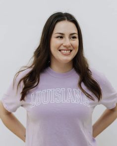 a woman wearing a purple shirt with the word louisiana in white on it's chest