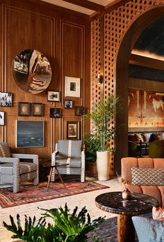 a living room filled with lots of furniture next to a wall covered in wooden paneling