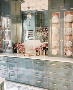 a kitchen with blue cabinets and marble counter tops, gold trimmings and pink flowers