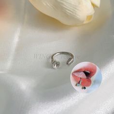 a close up of a ring on a white cloth with a flower in the background