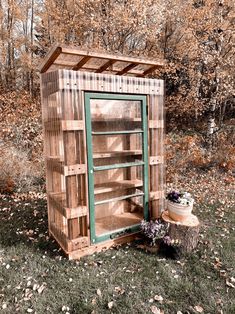 an old outhouse is sitting in the grass next to a potted planter