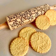 three cookies on a cookie sheet next to a rolling pin