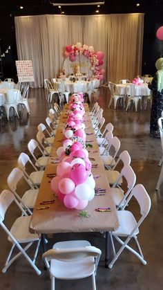 a long table with pink and white balloons on it