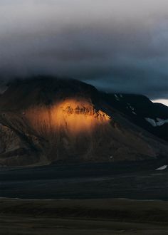 the mountains are covered in clouds and light shining on them at sunset or sunrise time