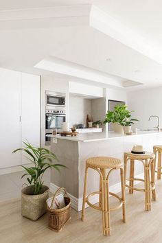 a kitchen with stools and plants in the center, along with an island counter