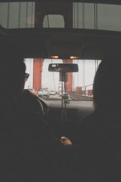 two people are sitting in the back seat of a car looking out at the golden gate bridge