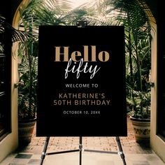 a welcome sign in front of an arch with palm trees and potted plants behind it